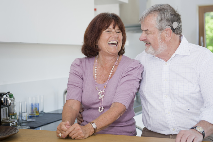 Man with a cochlear implant laughs with his wife