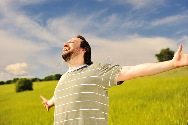 Happy man in a field with arms open wide