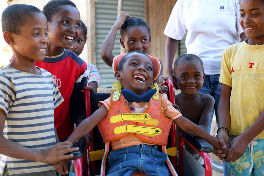 Young boys around a bow in a wheelchair, laughing